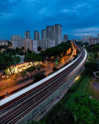 Light trails on street amidst buildings in city against sky