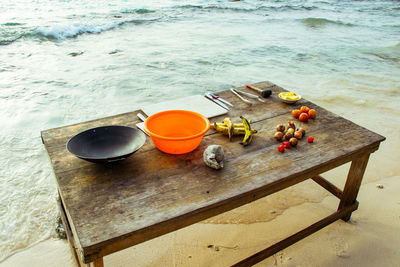 High angle view of containers with fruits and vegetables on table at beach