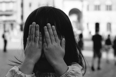 Close-up of girl covering eyes on footpath