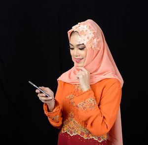 Midsection of woman holding smart phone against black background