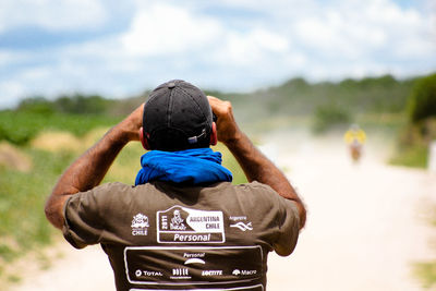 Rear view of man photographing against sky