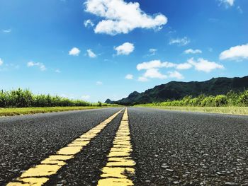 Surface level of empty road against blue sky