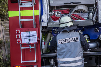 Firefighter standing against vehicle