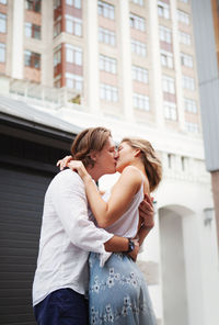 Couple kissing and embracing while standing together on city street. portrait of romantic model