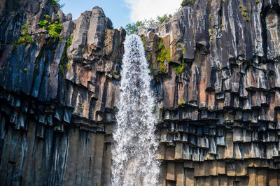 Low angle view of waterfall amidst rocks and mountains