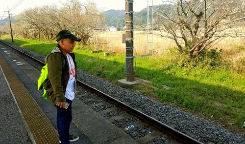 Side view of boy standing on railroad track