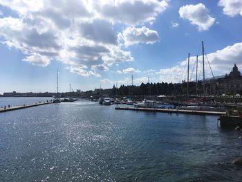 Sailboats in sea against cloudy sky