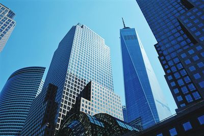 Low angle view of modern glass buildings in city against sky