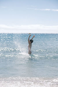 Side view of man running in sea against sky