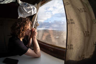 Rear view of woman looking through window