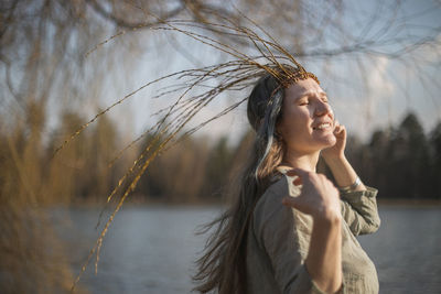 Side view of young woman standing against lake