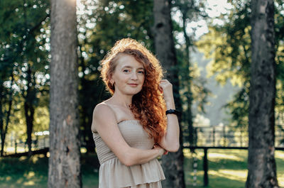 Portrait of young woman standing against trees