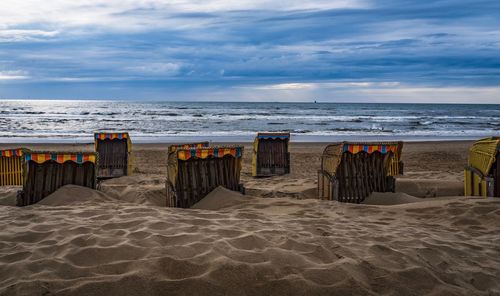 Hooded chairs on beach against sky