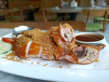 Close-up of roasted chicken with herbs in plate on table