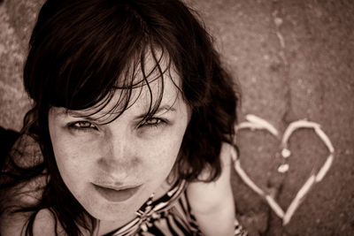 High angle portrait of young woman with heart shape on footpath