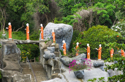 Statues on rock against trees and plants