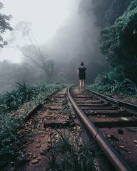 Rear view of person standing on railroad track