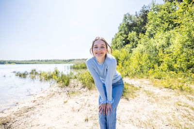 Portrait of young woman standing against lake