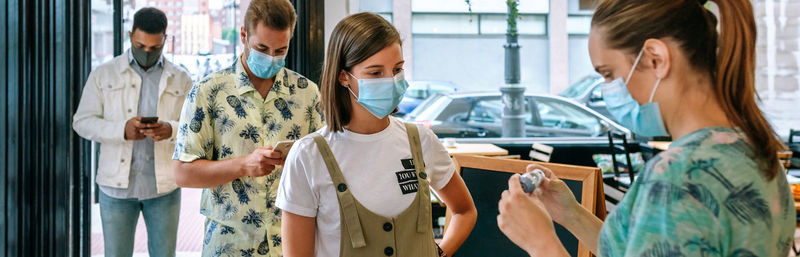 Woman checking temperature of customers at cafe