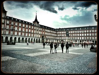 Tourists in front of building against cloudy sky