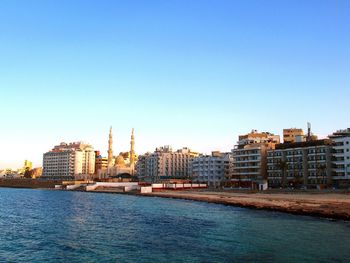 River amidst buildings in city against clear blue sky