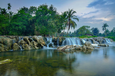 Scenic view of waterfall in forest against sky