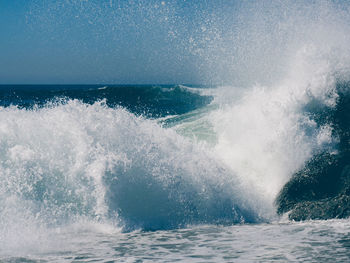 Waves splashing on sea against sky