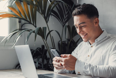 Young man using mobile phone while sitting on table