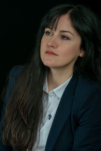 Portrait of beautiful young woman against black background