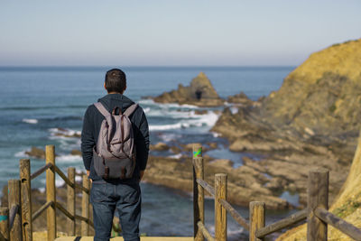 Rear view of man looking at sea against sky