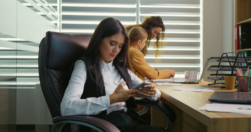 Female nervous chatting on the phone being in the office with two coworkers. 