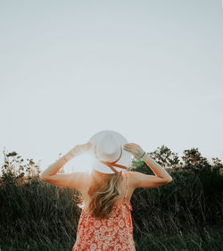 Rear view of woman standing on field against clear sky