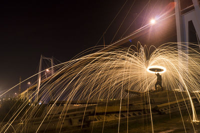 Man with wire wool at figueira da foz bridge against sky during night
