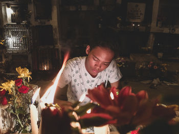 Teenage boy sitting by lit candles at home