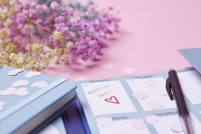 Heart-shaped confetti and calendar on pink background