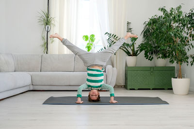 Boy doing headstand on exercise mat at home