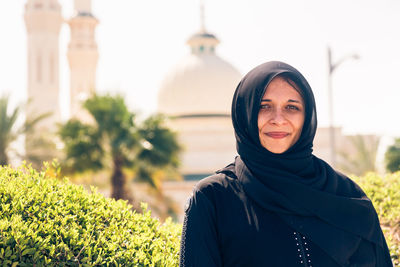 Portrait of woman wearing traditional clothing while standing against mosque