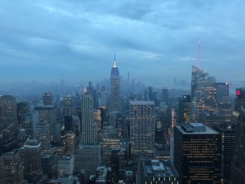 Aerial view of buildings in city against cloudy sky