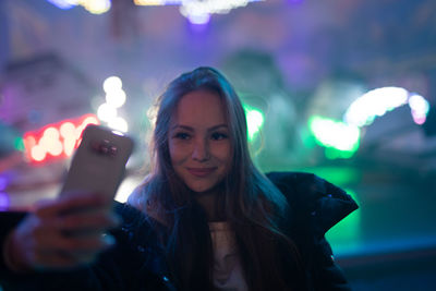 Portrait of young woman using mobile phone at night