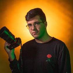 Young man photographing against orange sky