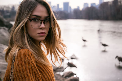 Close-up of beautiful woman with blond hair standing against lake