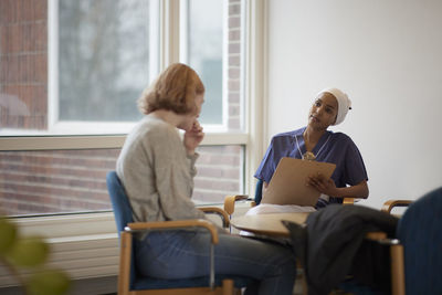 Female doctor talking to teenage patient and taking notes