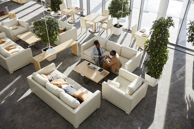 Business colleagues discussing business strategy sitting on sofa in modern office