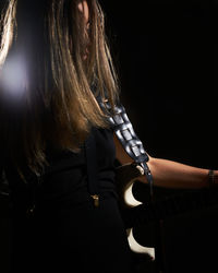 Woman playing guitar against black background