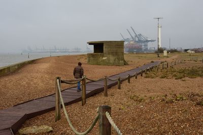 Rear view of man on railing against sky