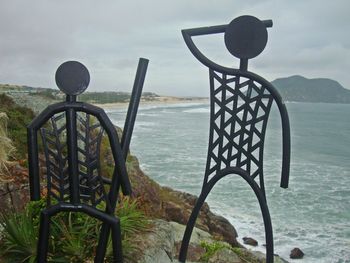 Metal railing by sea against sky