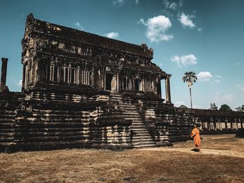 Man standing by historic building against sky