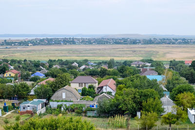 Trees and houses on field against sky