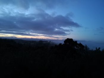 Silhouette trees on landscape against sky at sunset