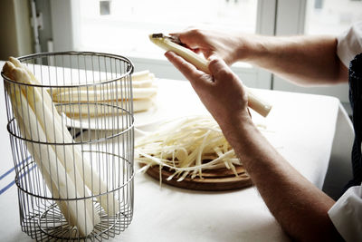 Cropped hands cutting white asparagus at home